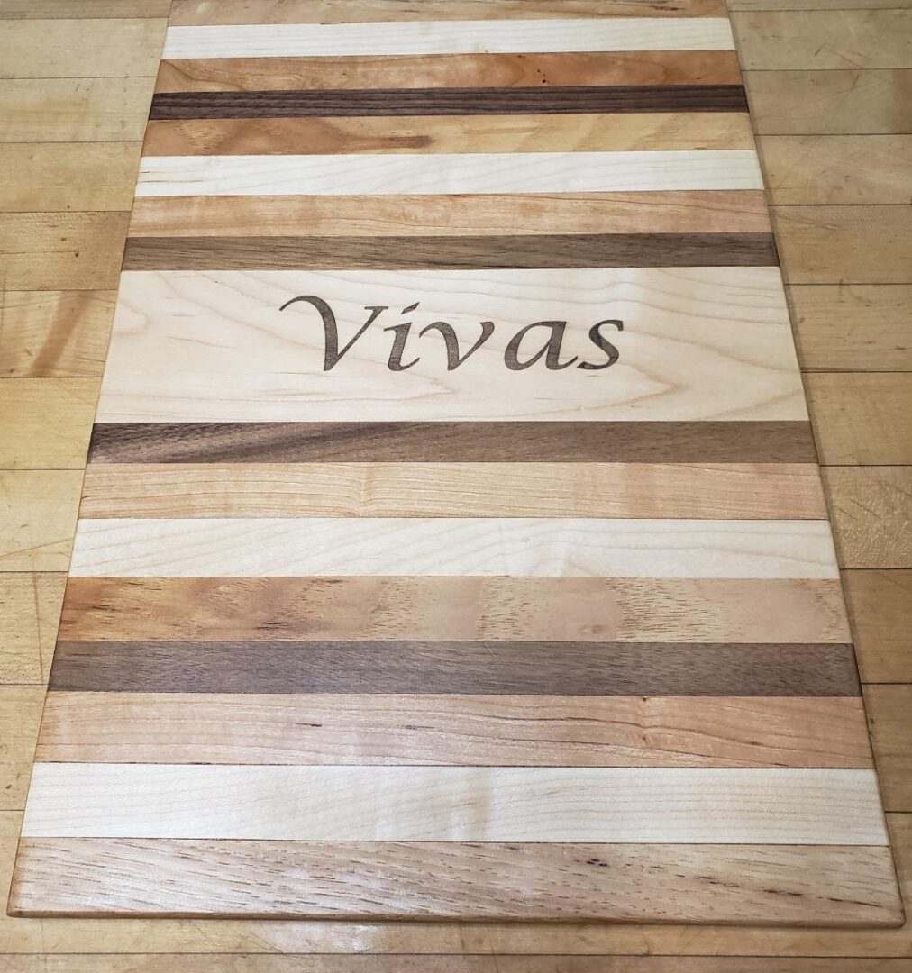 A cutting board with the word vivas kept on a wooden background