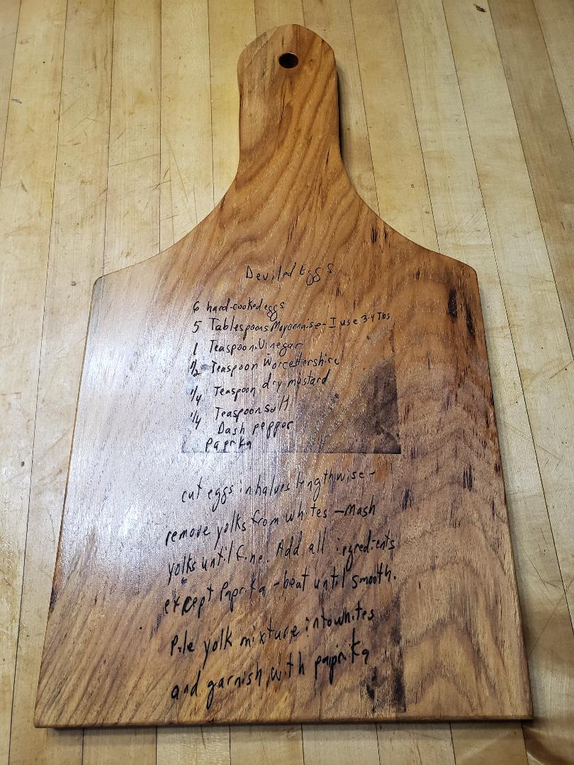 recipe cutting board with word carved on it and kept on a wooden floor